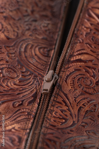 Zipper on dark brown red leather with floral print. Detail of boot.