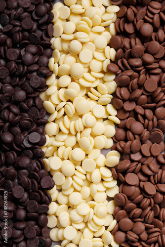 Dark, white and medium dark chocolate drops for making chocolate, candies, cakes as a background. Tempered chocolate confectionery concept. Chocolate background.