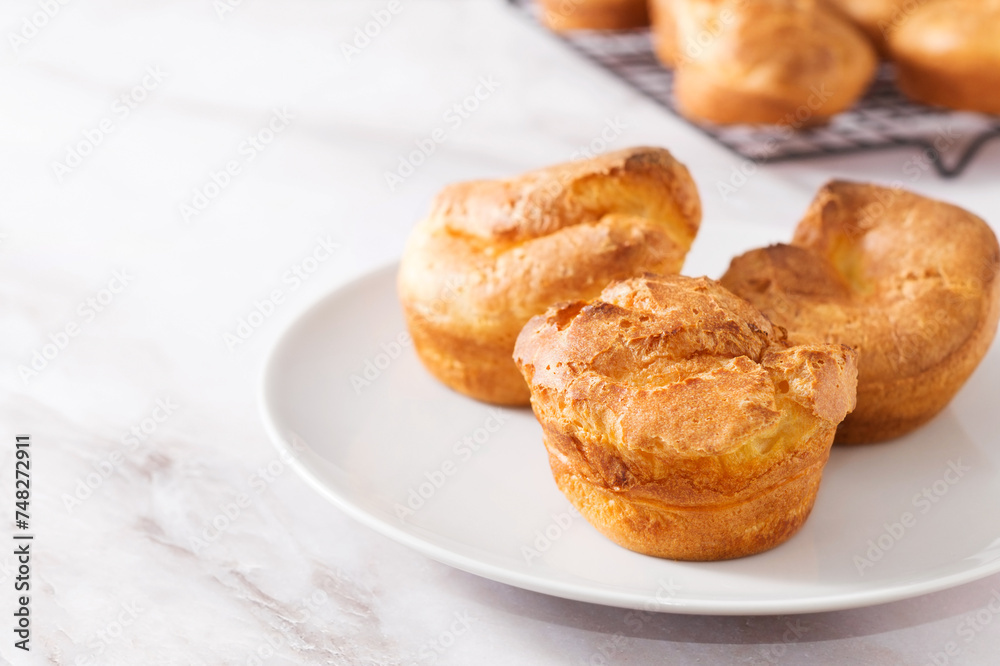Popovers or Yorkshire pudding on a white plate on a white background, appetizer, breakfast, copy space