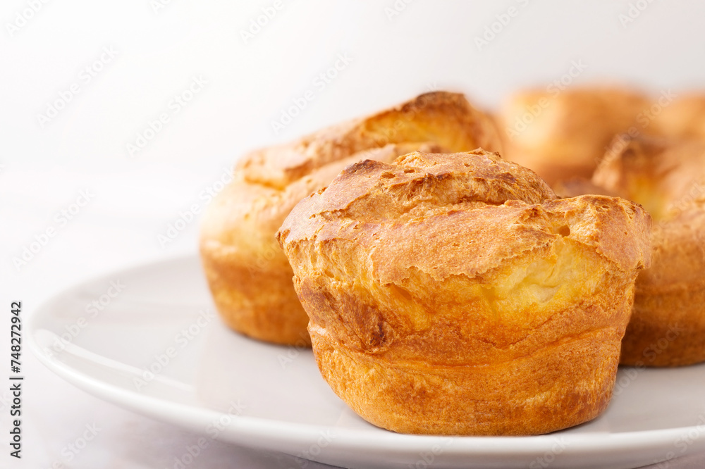 Popovers on white plate on a white background,close up. Yorkshire pudding as a easy cooking breakfast, tasty food, light snack Popovers on white plate on a white background,close up. Yorkshire pudding as a easy cooking breakfast, tasty food, light snack