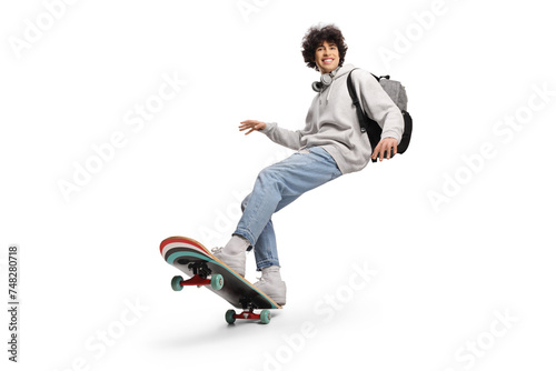 Cool young man with headphones and backpack riding a skateboard