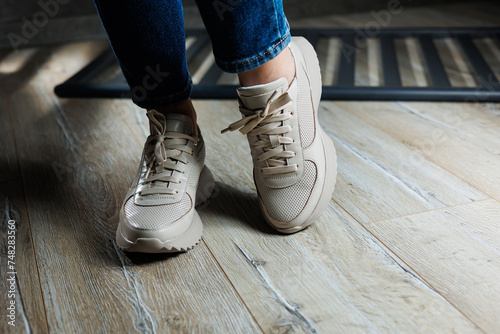 Beige women s sneakers. Collection of women s leather shoes. Female legs in leather beige casual sneakers. Stylish women s sneakers.