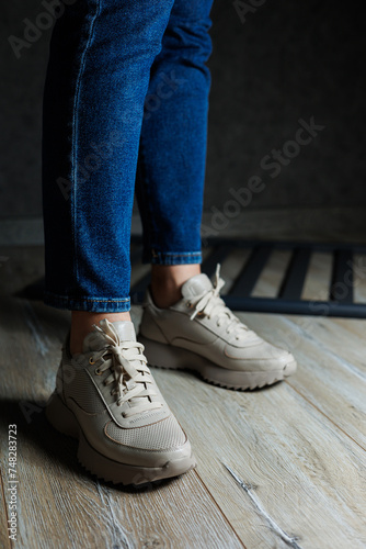 Collection of women's leather shoes. Female legs in leather beige casual sneakers. Stylish women's sneakers.