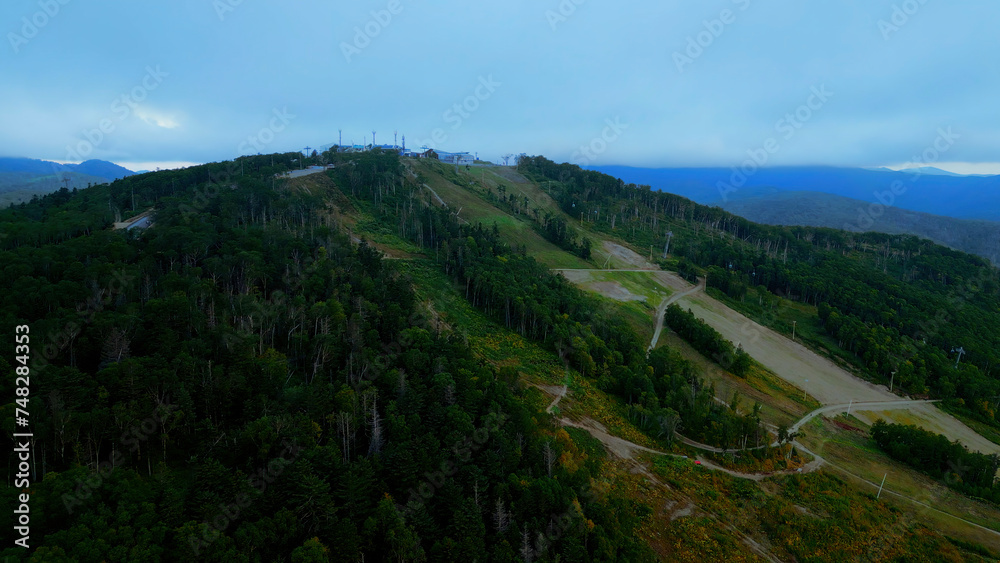 Aerial view of cable cars in mountains. Clip. Travel and outdoor activities, hills, coniferous trees and blue sky.
