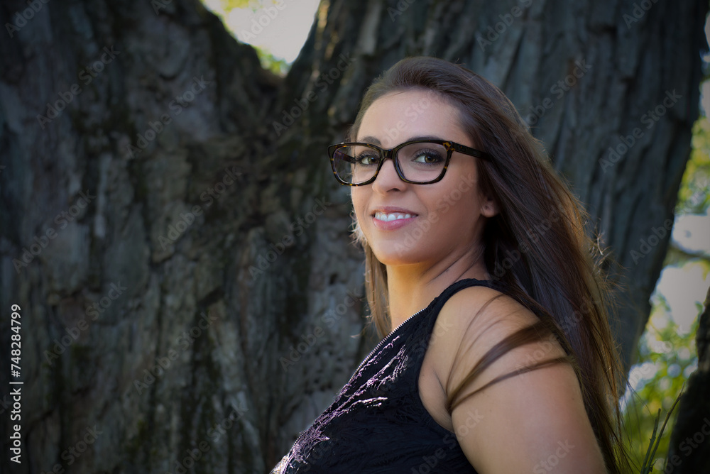 young woman long hair and eye glasses resting on tree at the park in sunshine young woman long hair and eye glasses resting on tree at the park in sunshine