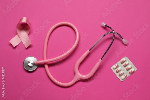 Pink ribbon, stethoscope and pills on color background, flat lay. Breast cancer awareness