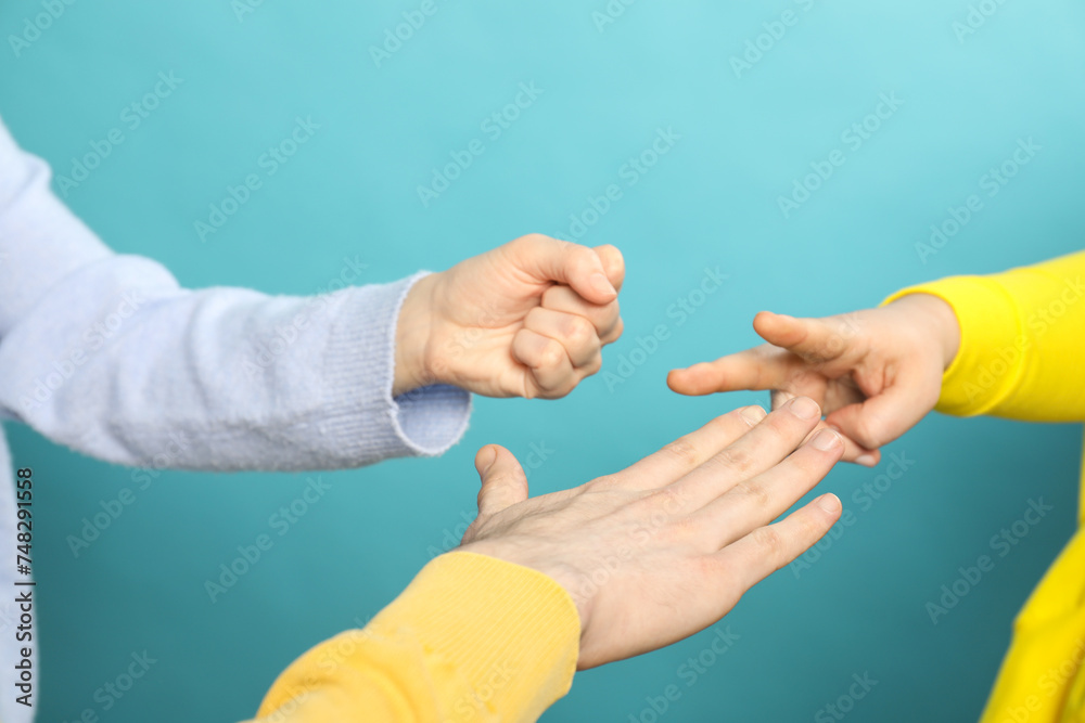People playing rock, paper and scissors on light blue background, closeup - obrazy, fototapety, plakaty 