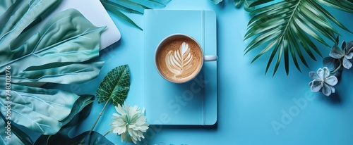 a notebook, coffee and a laptop on a blue table