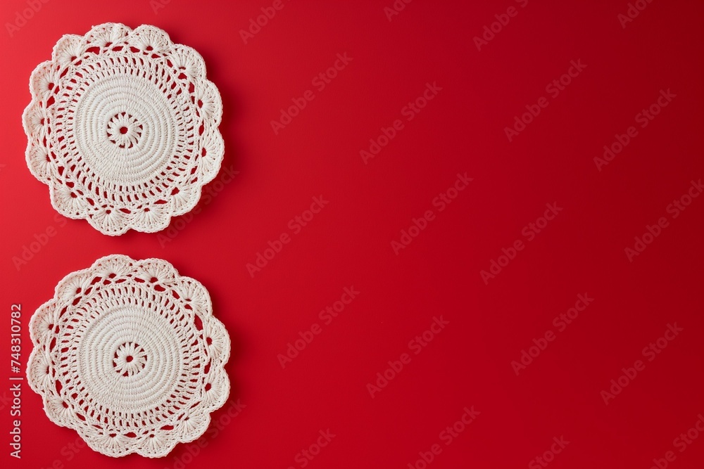 Two white crochet napkins against a red background with copy space. Two white crochet napkins against a red background with copy space.