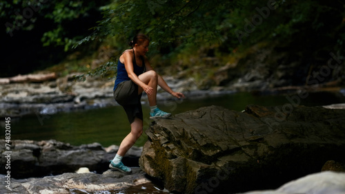 Young caucasian girl walking carefully on stony path and river. Creative. Concept of active lifestyle and hiking.