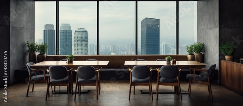A stylish dining room with wooden chairs and tables arranged neatly on a grey granite floor. The room features a large panoramic window offering a view of the Kuala Lumpur city skyscrapers.
