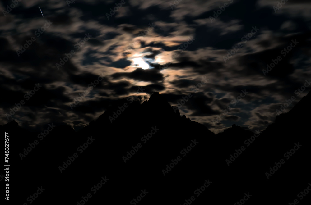 The clouds in front of the moon above the Tre Cime di Lavaredo. - obrazy, fototapety, plakaty 