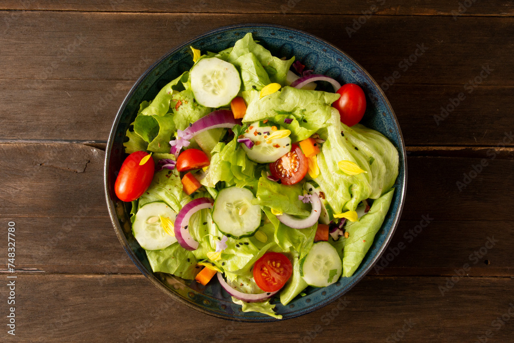 A Fresh salad bowl with lettuce , tomatoes, onions and vegetables in aerial top view