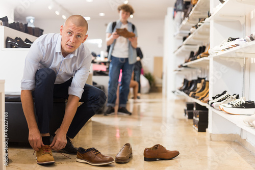 Handsome man trying on summer brown shoes in a shoe store