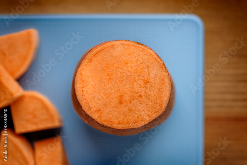 Top view of a blue cutting board with sliced sweet potatoes