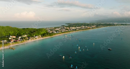 Paraw sailing over turquoise water, powdery white sand beaches in Boracay at dusk time. Philippines. photo