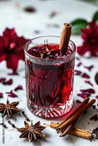 a glass of red liquid with cinnamon sticks and star anise