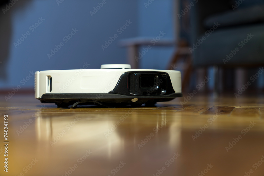 robot vacuum cleaner in modern smart home, robotic vacuum cleaner on wooden or laminate or parquet floor, cleaning dust on tile floors. Modern smart cleaning technology housekeeping. colorful back. robot vacuum cleaner in modern smart home, robotic vacuum cleaner on wooden or laminate or parquet floor, cleaning dust on tile floors. Modern smart cleaning technology housekeeping. colorful back.