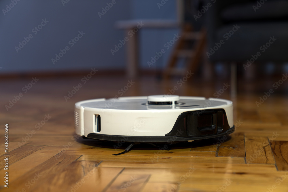 robot vacuum cleaner in modern smart home, robotic vacuum cleaner on wooden or laminate or parquet floor, cleaning dust on tile floors. Modern smart cleaning technology housekeeping. colorful back. robot vacuum cleaner in modern smart home, robotic vacuum cleaner on wooden or laminate or parquet floor, cleaning dust on tile floors. Modern smart cleaning technology housekeeping. colorful back.