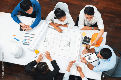 Top view banner of diverse group of civil engineer and client working together on architectural project, reviewing construction plan and building blueprint at meeting table. Prudent
