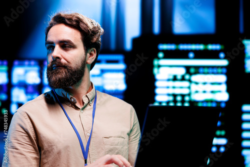 IT Specialist looking at operational servers in computer network security data center. Mainframes providing processing and memory resources needed for computational operations