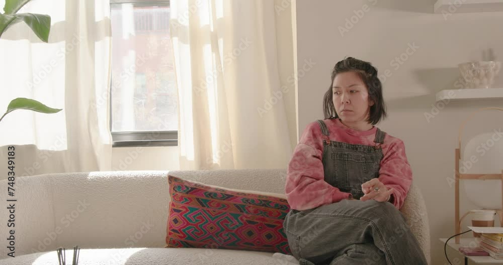 Young asian woman deep in thought on couch. Young asian woman deep in thought on couch.