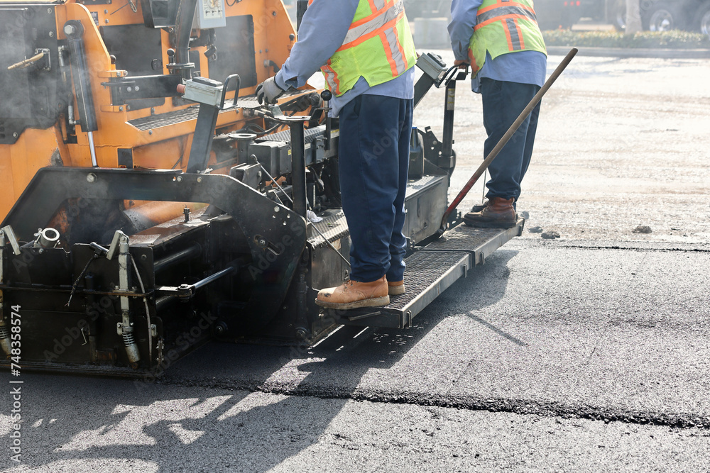 workers operate machinery for new asphalt