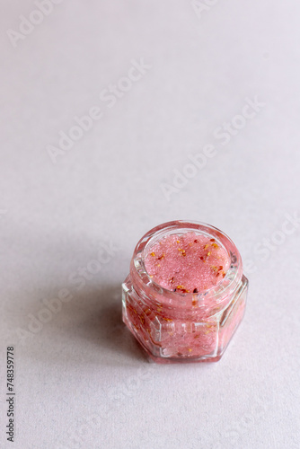 Pink lip scrub in a glass jar isolated on a beige seemless background
