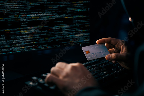 Cropped hands image in criminal anonymous male approaching credit card of personal information database for codding encryption scam program in privacy system at night at blue neon light room. Surmise.