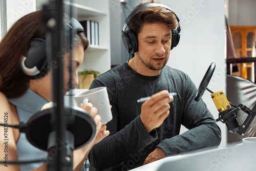 Host channel broadcasters discussing together, making advice for problem in live streaming with listeners surrounded sets of live streaming on radio talking show at comfy modern workplace. Postulate.