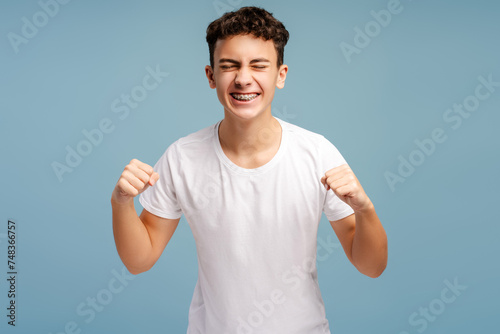 Excited strong teenager wearing stylish white t shirt rejoicing and supporting team