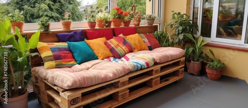 A wooden pallet couch is neatly arranged on a porch, providing a rustic and DIY touch to the outdoor space. The couch is set against the backdrop of the porch,