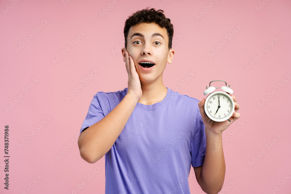 Shocked boy with dental braces holding alarm clock and screaming isolated Shocked boy with dental braces holding alarm clock and screaming isolated