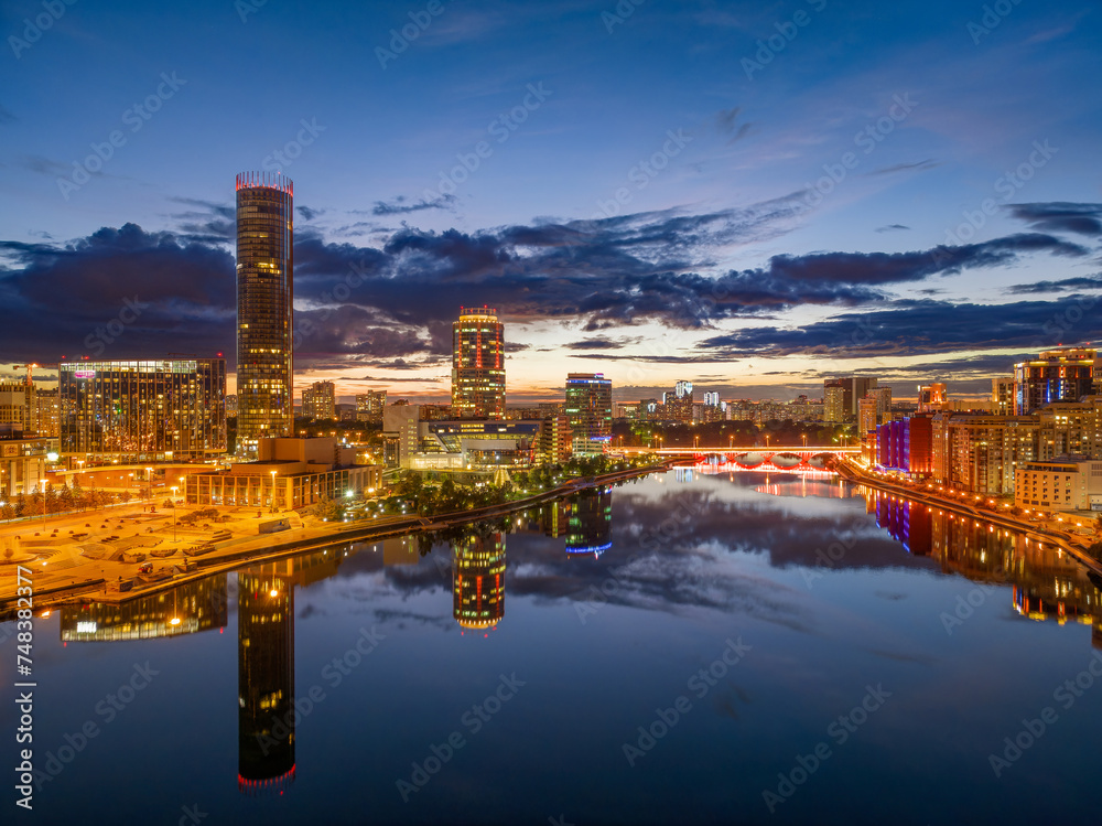 Fototapeta premium Yekaterinburg city and pond aerial panoramic view at summer or early autumn night. Night city in the early autumn or summer.