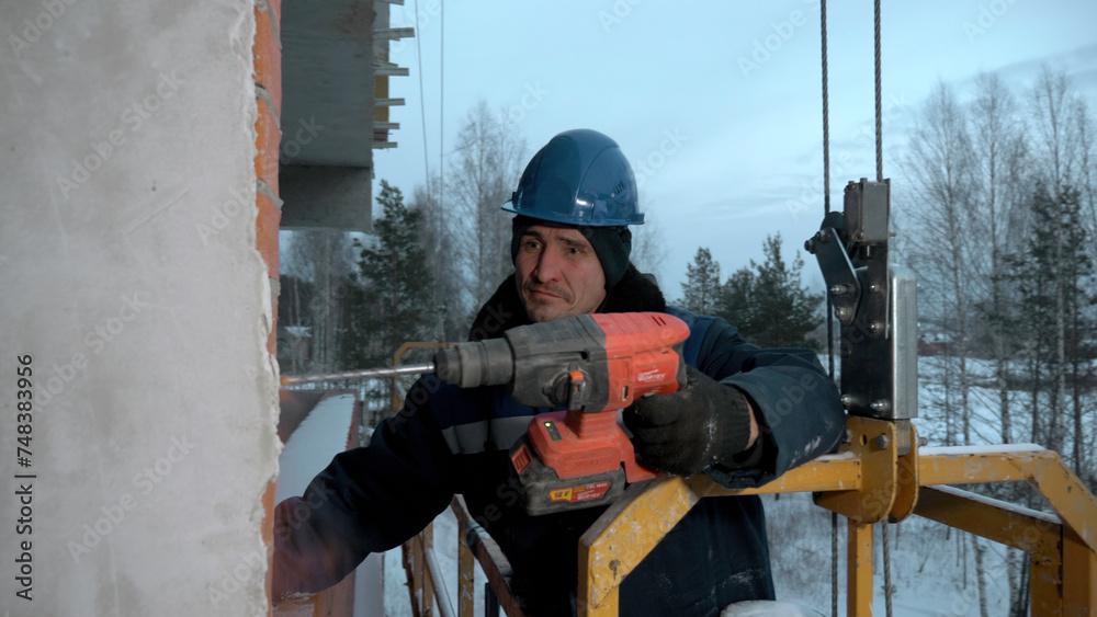 Man drills holes in a concrete wall. Clip. Industrial background of a builder at the construction site.