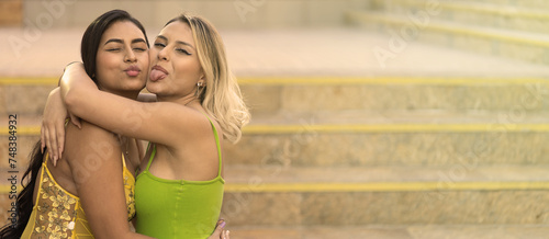 Two multiracial friends hug each other making funny face frienship concept