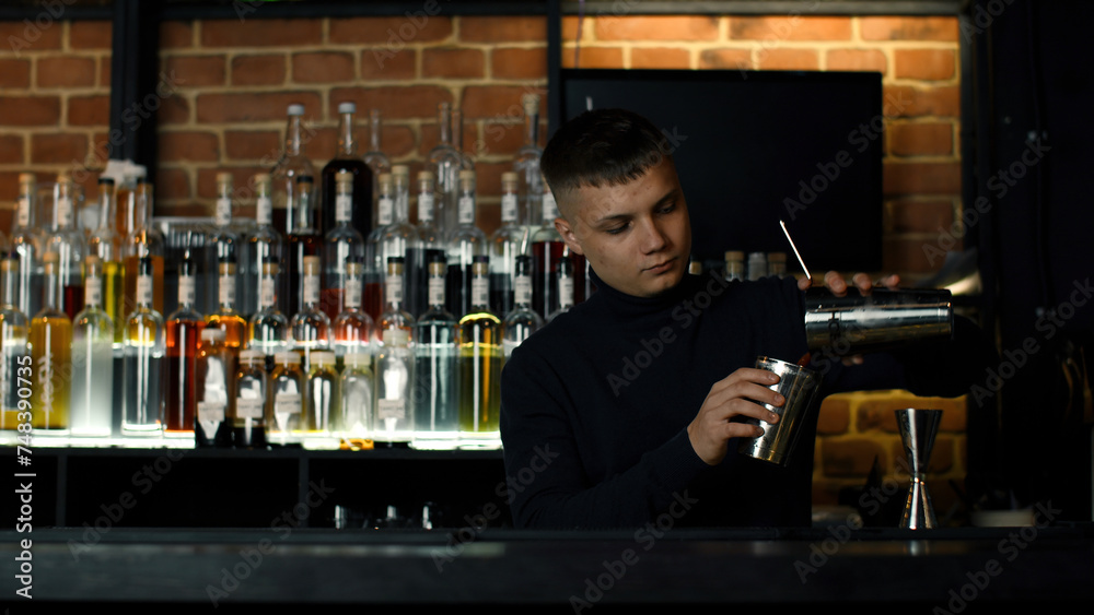 The process of preparing an alcoholic cocktail at the bar. Media. Young male bartender at work.