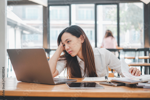 Business problem solving concept, A stressed young woman appears anxious as she concentrates on her laptop, possibly dealing with a tight deadline or challenging work in a bright office space.