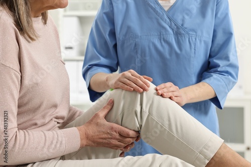 Arthritis symptoms. Doctor examining patient with knee pain in hospital, closeup photo