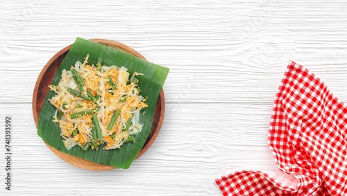 Selective focus Urap Sayur is Indonesian traditional food. a salad dish of steamed various vegetables mixed with seasoned and spiced, served on banana leaf and wood plate photo