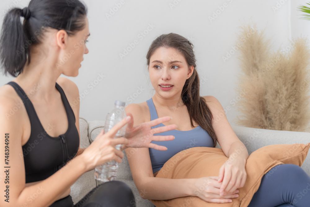 Group of happy sporty women wearing body stylish sportswear and talking together. waiting for yoga class.. healthy lifestyle and wellness. Couple women are relaxing and sitting at sofa in living room. Group of happy sporty women wearing body stylish sportswear and talking together. waiting for yoga class.. healthy lifestyle and wellness. Couple women are relaxing and sitting at sofa in living room.