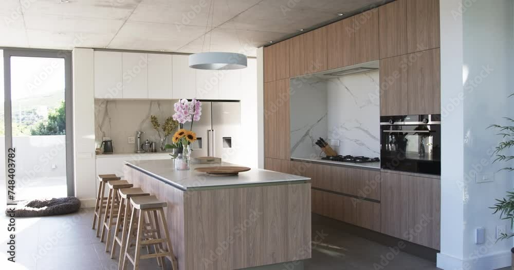 A modern kitchen features wood grain cabinetry and a central island with bar stools A modern kitchen features wood grain cabinetry and a central island with bar stools