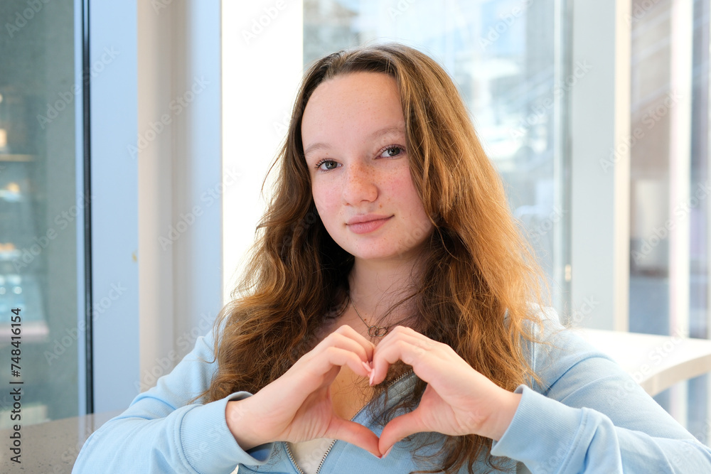 making heart with hands confession choice beautiful teen girl standing by the window holding hands at chest level folding positive sign peace in ukraine making heart with hands confession choice beautiful teen girl standing by the window holding hands at chest level folding positive sign peace in ukraine