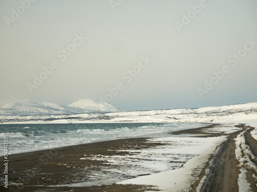 Driving by Northern sea black sand coast in winter  Hitokappu or Kasatka bay on Iturup  Stokap volcano in background  Kuril islands