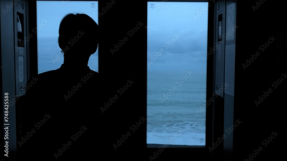 Man traveling by train and looking through the window at the sea. Stock clip. Beautiful late evening seascape from the moving train.
