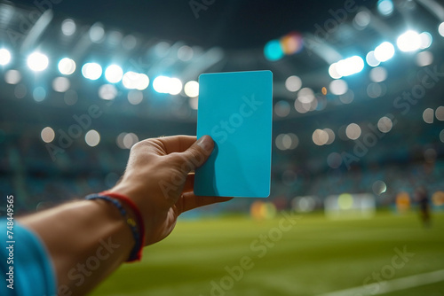 Referee hand holding up a blue card