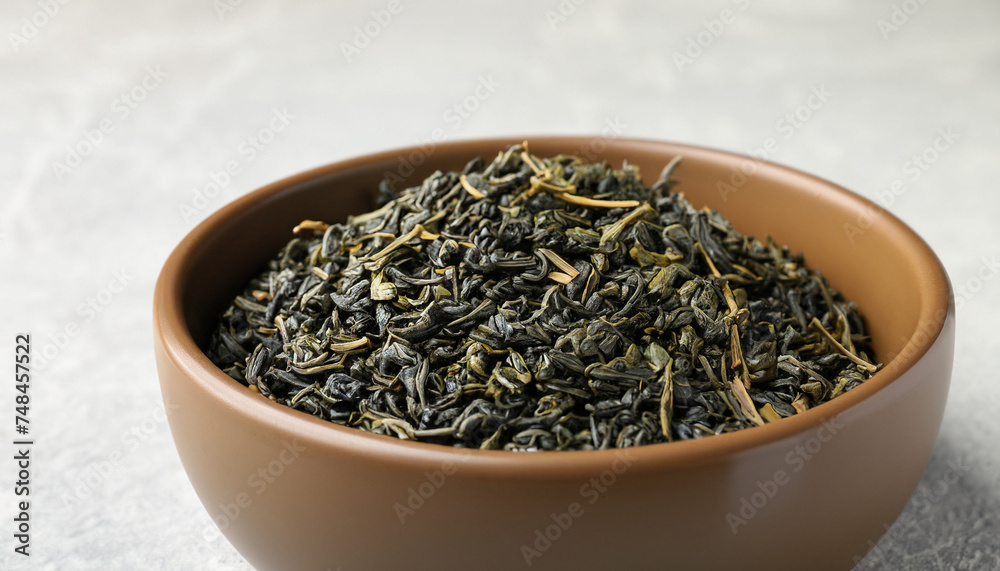 Bowl of dry green tea leaves on light background, closeup view with space for text Bowl of dry green tea leaves on light background, closeup view with space for text