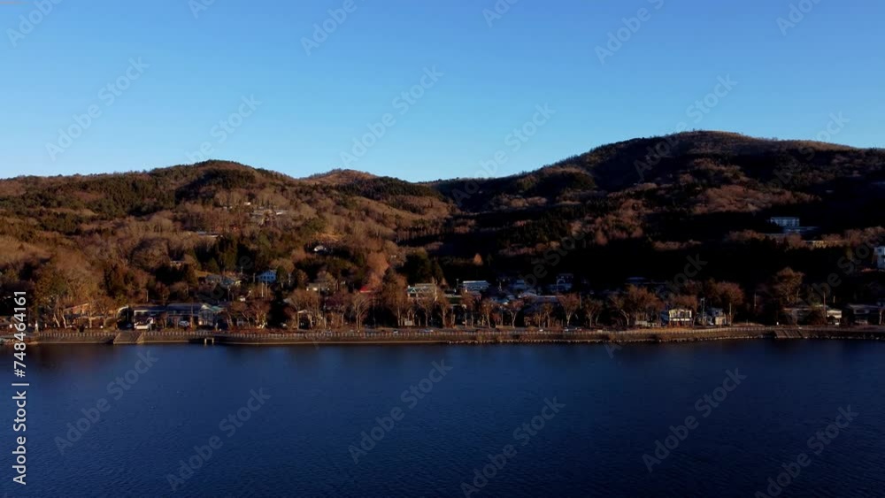 A serene lakeside town at dusk, with hills in the background and clear skies, aerial view A serene lakeside town at dusk, with hills in the background and clear skies, aerial view