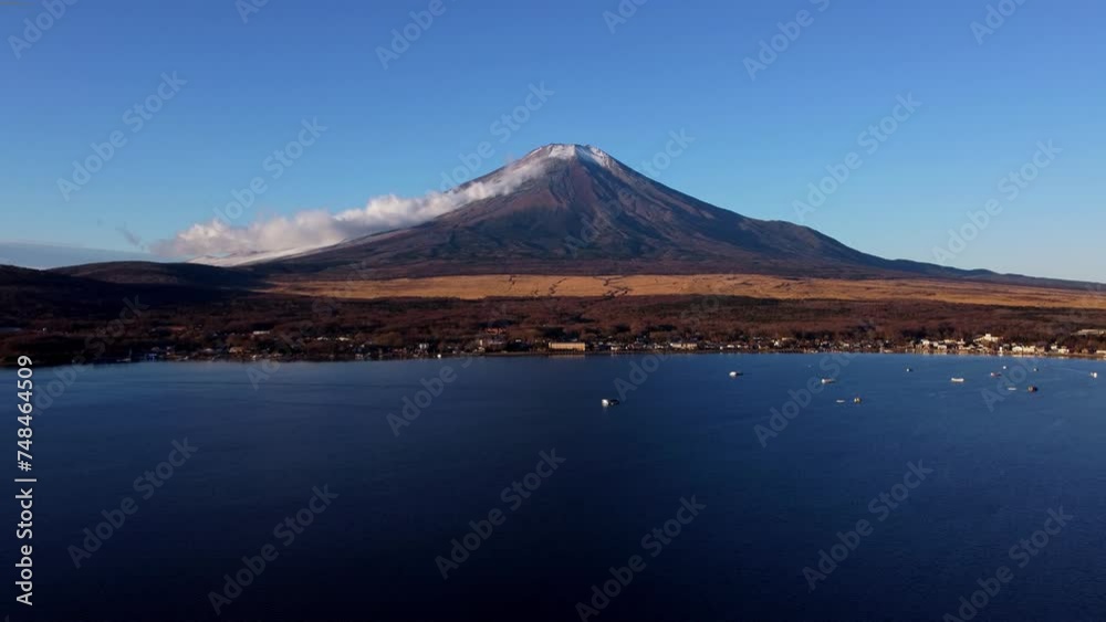 Mount Fuji seen across a calm lake with boats at dawn, clear blue sky Mount Fuji seen across a calm lake with boats at dawn, clear blue sky