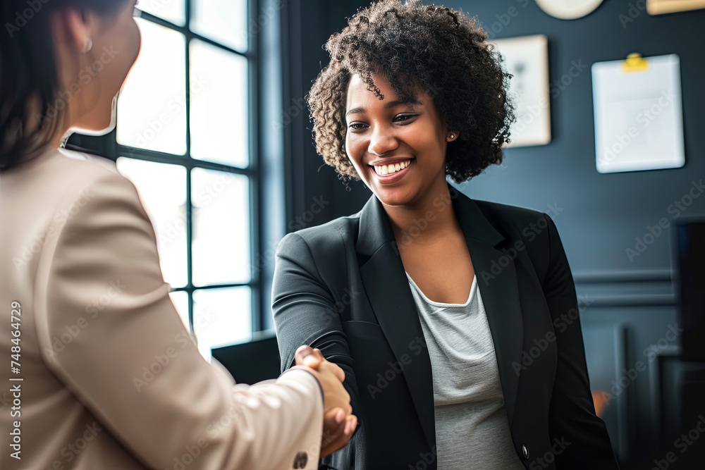 A businesswoman shaking hands with another businesswoman - obrazy, fototapety, plakaty 
